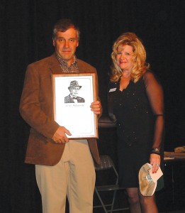 Dale Bahr gratefully accepts a plaque from Wisconsin Aviation Hall of Fame President Rose Dorcey. Bahr is the grandson of 2005 Inductee Wendell McEldowney. A plaque is presented to the inductees or their families, while another is permanently displayed at