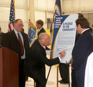 Bill DeCota waits as James Coyne signs the pledge. “The best way to work through issues of safety, security and noise is to broaden the dialogue, to include those directly connected to airport operations,” Coyne said.