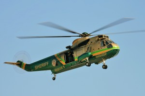 A Sikorsky SH-3H Sea King from the Los Angeles County Sheriff’s Department’s search and rescue team passes over the field.