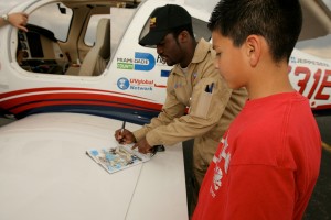 Barrington Irving signs an autograph for an admiring fan. He’s unofficially the youngest person ever to fly solo around the world and is the first of African descent to do so.