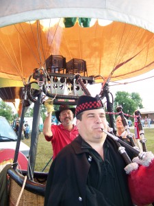 Ken Tadolini (background), RE/MAX balloon pilot, lights the burners while Bennett Holmes (foreground) plays the bagpipe during the fifth annual Rocky Mountain Balloon Festival.