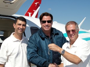 Vern Raburn (right), founder and CEO of Eclipse Aviation, accompanied by Mike McConnell (left), VP of marketing and sales hands, hands John Travolta the keys to his new Eclipse 500.