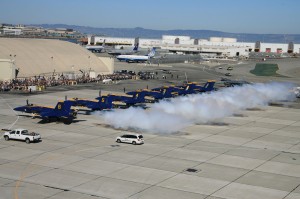 The Blue Angels show begins on the ground, demonstrating precision while marching to the planes, getting in the cockpits starting the engines, and maintaining a synchronized puff of smoke during takeoff, even though the air show crowds are miles away.