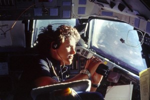 Astronaut Kathryn D. Sullivan, on board Challenger STS-41-G, uses binoculars for a magnified view of Earth through Challenger's forward cabin windows.