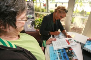 Laurie Lips looks on as Patty Wagstaff autographs a copy of “Living Legends of Aviation.” She’s one of 25 legends in the book, written by Di Freeze.