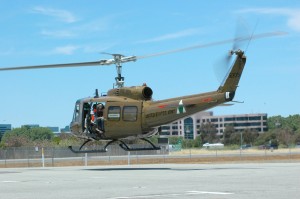 A UH-1 Huey takes off with a load of media photographers.