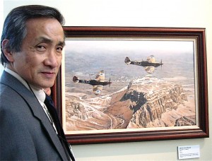 Ronald T.K. Wong of England displays his painting, “Merlins Over Masada,” depicting two Israeli Air Force Spitfire Mk.IXs flying over historic Masada.